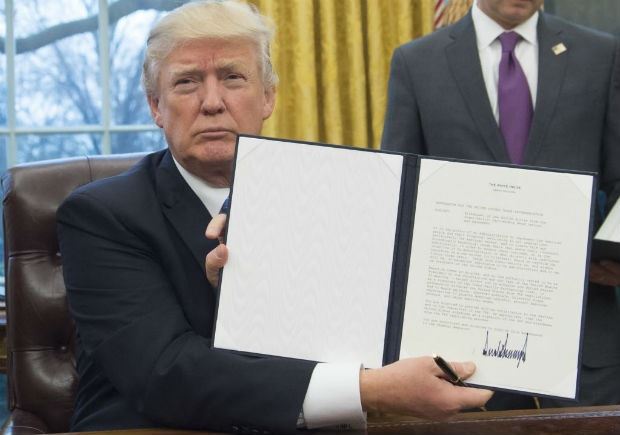 O presidente Donald Trump mostra decreto em que retira os EUA da TPP